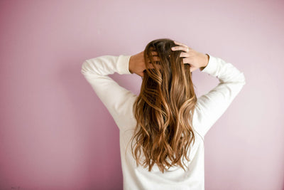 A close-up of a person examining their thinning hair in the mirror, highlighting concerns about hair loss and scalp health.