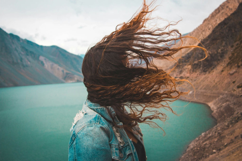 Woman on a lake who uses Divi Volumizing Shampoo & Conditioner.